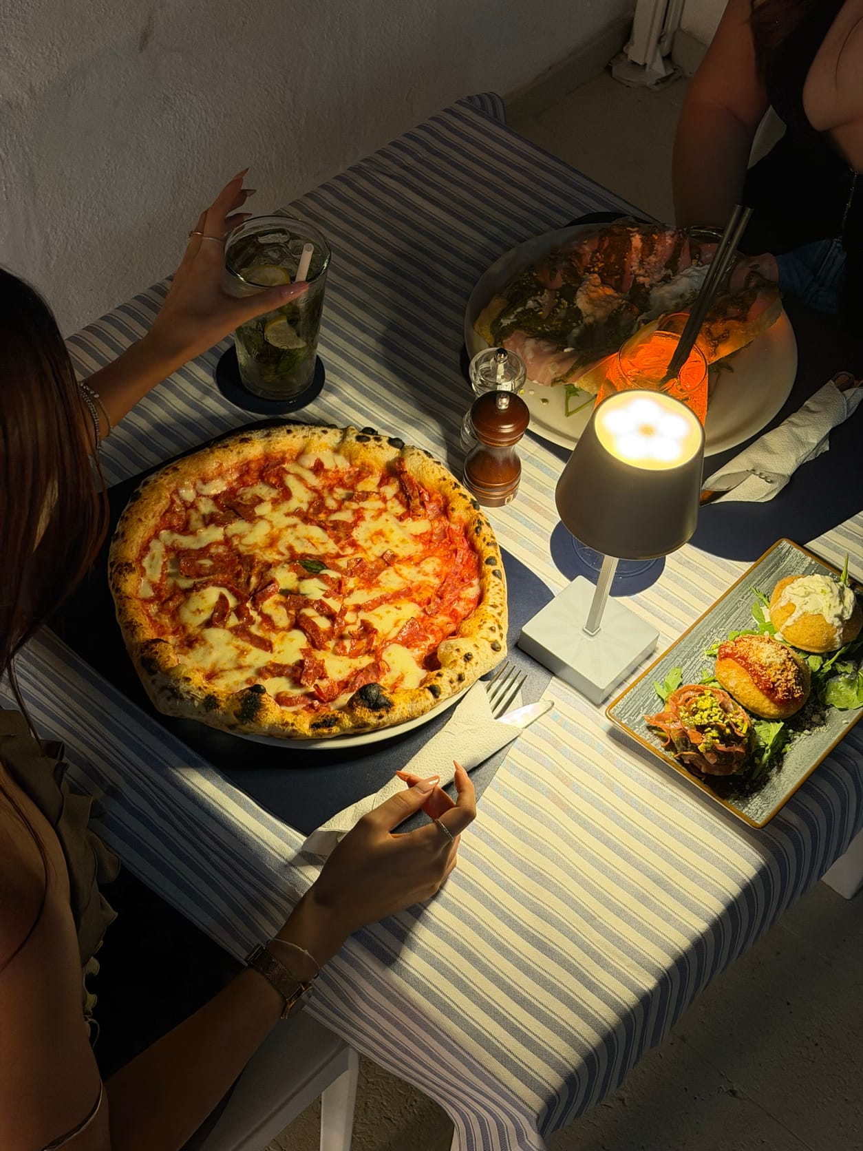 Tavolo la sera con pizza, mojito, lampada e fritti sulla terrazza di Marina Due Golfi